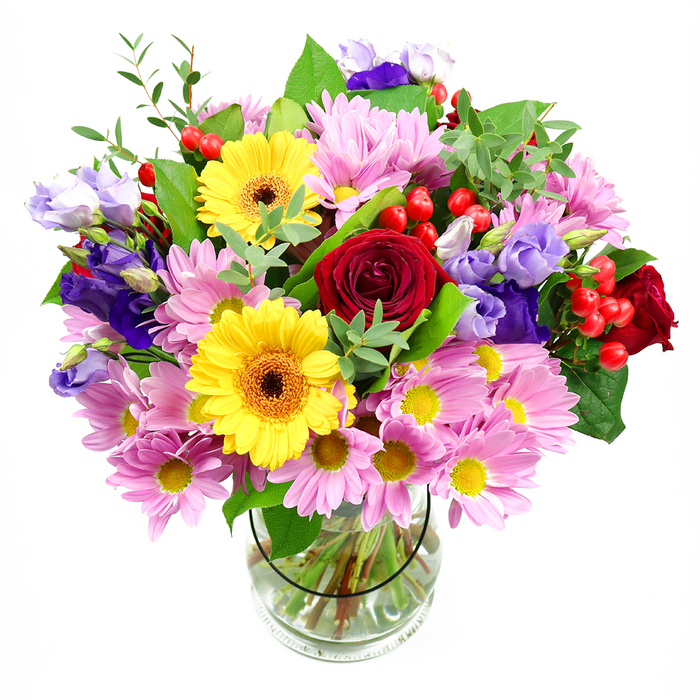 This image captures a generously sized, mixed-flower bouquet presented in a clear glass vase, the arrangement glowing against a bright white background as though just placed on a kitchen table in a Bethnal Green townhouse. The bouquet is built around a core of luxurious deep red roses, their layered, velvety petals unfurling in classic spirals that suggest romance and heartfelt emotion. Radiating out from these roses are plentiful clusters of soft pink daisies or chrysanthemums, each bloom composed of many slender petals and a small yellow centre, creating a cushion of colour that feels gentle and welcoming, like a friendly chat with neighbours near Museum Gardens. Punctuating this soft pink mass are striking yellow gerbera daisies, their large, sun-like faces and warm brown-orange centres giving the design an instant feeling of happiness and celebration. Interlaced through the arrangement, tall stems of lisianthus in rich purple and muted lavender tones arc gracefully, their bell-shaped flowers adding a cool, refined note that tempers the brighter hues. Here and there, round red hypericum berries cluster on slender stalks, glistening like tiny cherries and lending an additional layer of texture and visual interest. The flowers are held together by a wealth of greenery, from wide, dark green leaves that offer a strong base to airy, light-green sprays that soften the edges, enhancing the bouquet's natural, garden-like charm. The transparent vase reveals the tidy bundle of stems and the clean water that keeps them fresh, subtly showcasing the florist's craftsmanship and attention to detail. Altogether, the arrangement exudes an atmosphere of joyful gratitude and thoughtful care-ideal for birthdays, thank-you gifts, or a bright pick-me-up delivered anywhere around Bethnal Green, from Globe Town to the streets near Cambridge Heath.